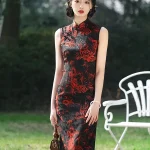 Front view of women's long vintage floral sleeveless high cut qipao (cheongsam) with bold red dragon print on black fabric, model standing outdoors holding a small brown handbag.