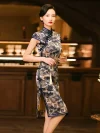 Elegant model wearing a misty blue bamboo pattern print brocade cheongsam dress, holding a traditional hand fan, standing in a vintage bar setting to showcase the dress's mandarin collar, frog buttons, and high slit.