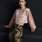 Mid-shot of the misty pink modernized jacquard short qipao top, showcasing the intricate wave jacquard texture, traditional frog button placket, and cropped silhouette; elegant modern qipao top with a subtle pink hue