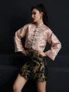 Side view shot of the misty pink modernized jacquard short qipao top, showing the flowing wide sleeves, subtle wave jacquard pattern, and cropped fit; versatile modern qipao top suitable for both casual and dressy occasions
