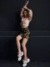 Full-body fashion shot of the misty pink modernized jacquard short qipao top, featuring traditional frog buttons, high mandarin collar, and delicate wave jacquard pattern; paired with a tiger print mini skirt and sneakers for a trendy modern cheongsam top look