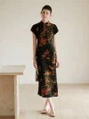 Full length view of a modern Chinese qipao dress, a slim fit black mulberry silk cheongsam with vibrant lychee and floral print. The elegant woman stands in a bright, minimalist room, highlighting the dress's tailored silhouette.