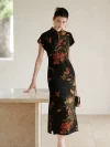 Woman leaning on a light stone countertop, wearing a modern lightweight short sleeve cheongsam dress. This black mulberry silk qipao with lychee print shows the dress's natural drape and elegant fit.
