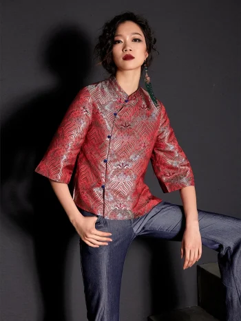 Front view of the women's modern Chinese red jacquard satin qipao top, showcasing three-quarter sleeves and traditional frog buttons; styled with blue jeans for a trendy cheongsam top look
