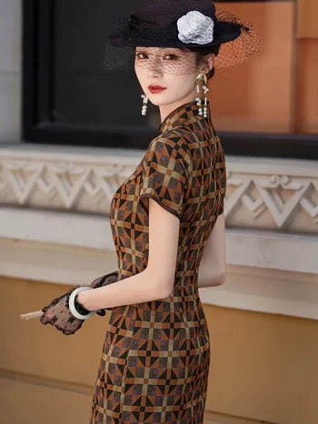 Back-side view of a women's Old Shanghai checkered cheongsam, a long qipao dress with a vintage geometric checkered pattern. The model poses near a historic building, showcasing the tailored fit, short sleeves, and high slit from the side, styled with period accessories including a net hat and drop earrings.
