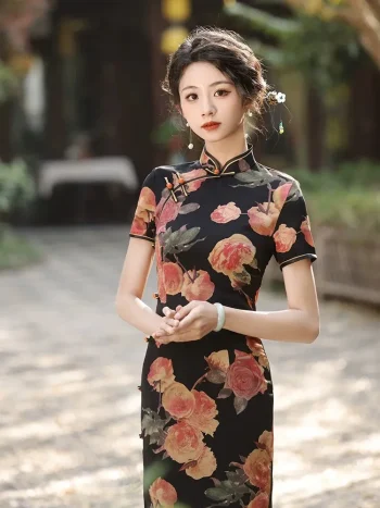 Front view of women's Old Shanghai peony pattern short sleeve cheongsam (qipao) with black base and vintage rose print, model standing outdoors with hands clasped, featuring elegant stand-up collar and traditional frog buttons.