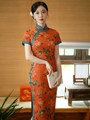 Vintage Old Shanghai style long cheongsam (qipao) in tangerine red with peony floral print and blue trim, elegant women's traditional Chinese dress, model holding a book.