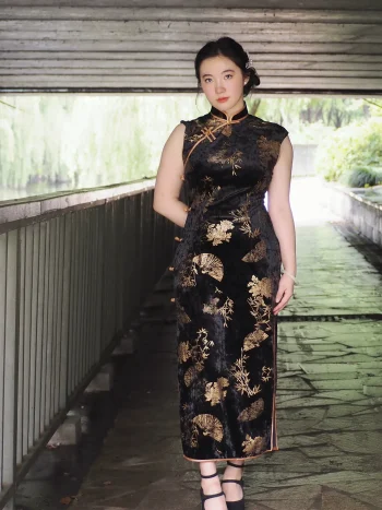 Full-body styled look of the black chinese cheongsam dress, a Chinese Black Sleeveless Plus Size Long Daily Cheongsam with classic gold bamboo and fan motifs. This qipao black dress is paired with modern accessories, showcasing its versatility as a daily wear piece for plus size women.