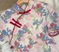 Close-up view of the mandarin collar and red frog buttons on a retro plus size floral short sleeve cheongsam dress, highlighting the vibrant print and classic details of this plus size cheongsam dress.