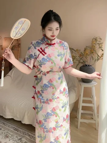 Woman in a retro plus size floral short sleeve cheongsam dress, standing pose with a hand fan in a soft-lit home interior, highlighting the form-fitting silhouette and delicate print of this plus size cheongsam dress.