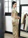 Side-back view of a mulberry silk printed midi cheongsam, showing the high side slit, traditional frog buttons, and floral print as the model stands by a mirror.