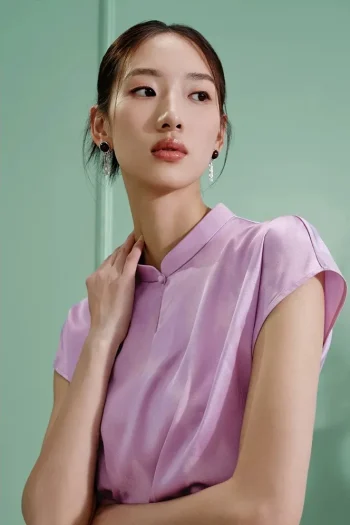 Close-up shot of a purple modern cheongsam shirt, women's mulberry silk qipao top with water drop collar and smooth satin texture, showing the elegant neckline design.