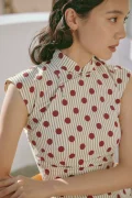 Close-up detail of a cotton qipao dress showing the traditional handcrafted frog button and polka dot-stripe print on premium fabric.