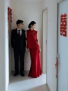 Red Chinese Cheongsam Dress - Bride in 2 piece cheongsam holding hands with groom, wearing textured red mandarin collar vest and maxi skirt set in a wedding hallway with double happiness decor, elegant bridal cheongsam for photos.