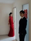 2 Piece Red Chinese Cheongsam Dress - Bride in modern two-piece cheongsam with beaded floral frog buttons, standing in a hallway for first look moment with groom, wearing red sleeveless top and flowing maxi skirt for wedding day.