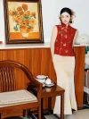 2 Piece Red and Gold Qipao - Chinese modern qipao with gold floral sequins on red sleeveless vest, paired with cream satin maxi skirt, posing in cozy home setting with teaware and sunflower painting