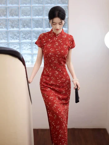 Elegant woman walking down stairs in a red base fresh floral slim fit long qipao, showcasing the form-fitting silhouette and traditional mandarin collar in a bright indoor setting.