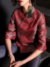 Close-up detail shot of the red jacquard satin fabric on the modern Chinese cheongsam top, highlighting the intricate wave pattern, blue frog buttons, and high collar design of this women's qipao top