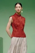 Model wearing a red cheongsam top modern style, a women's red chinese slim fit jacquard cheongsam top with mandarin collar, styled with statement gold earrings in a minimalist studio.