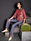 Side view of the women's red jacquard satin qipao top worn by a model leaning against a cactus planter, styled with flared jeans; contemporary cheongsam top with traditional wave pattern