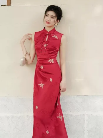 Side view of women's red Chinese cheongsam dress, sleeveless modern wedding qipao with teardrop mandarin collar, ruched waist design, and subtle floral embroidery for summer bridal wear