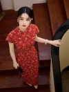 Top view of a woman in a red floral Chinese qipao dress standing on wooden stairs, highlighting the delicate floral print and pearl frog buttons on the front placket.