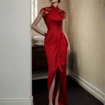 Model in a red floral embroidery satin wedding qipao dress, elegant lace qipao red with sheer embroidered short sleeves, high slit, and mandarin collar, posing in a vintage-style corridor.