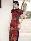 Close-up shot of a woman wearing a red floral vintage silk qipao dress, leaning against a white wall to showcase the peony print fabric, mandarin collar, and short sleeves.