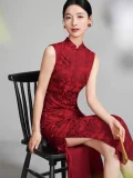 Woman in a deep red floral jacquard sleeveless chinese qipao, vintage-inspired long cheongsam dress sitting on a traditional wooden chair, elegant formal wear for weddings or events.