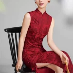 Woman in a deep red floral jacquard sleeveless chinese qipao, vintage-inspired long cheongsam dress sitting on a traditional wooden chair, elegant formal wear for weddings or events.