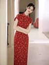Woman wearing a red base fresh floral slim fit long qipao, standing with arms crossed in a bright arched corridor, showing the dress's elegant lines and vintage charm.