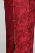 Close-up detail of red floral jacquard qipao fabric, highlighting the intricate pattern, traditional side frog buttons, and high side slit on this elegant vintage chinese cheongsam.