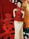 Modern Red and Gold 2 Piece Qipao - Bridal two-piece qipao with gold sequin flower embroidery on red peplum top, paired with ivory satin mermaid skirt, posing at romantic wedding setting with red curtain decor