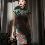 Full-body view of a model wearing the women's vintage red and green floral pattern midi cheongsam, a classic traditional chinese qipao dress. The flowing velvet drape, detailed prints, and elegant silhouette of this timeless cheongsam are showcased in soft studio lighting, blending traditional charm with modern styling.