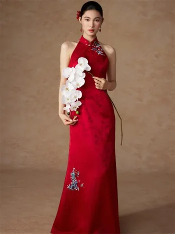 Model wearing a stunning red stand collar long modified cheongsam dress, a sleek halter-neck long qipao dress with subtle jacquard texture and side floral embroidery, blending modern silhouette with classic qipao chinese elegance.