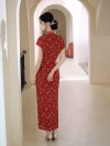 Back view of a woman in a red floral long qipao, standing in a light-colored arched corridor, showcasing the dress's flowing hem and elegant back silhouette.
