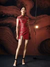 Model standing confidently in a vibrant red modern mini qipao dress, showcasing the traditional mandarin collar, green frog buttons, chest cutout, and tailored silhouette with a high side slit.