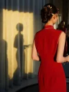 Qipao Sleeveless - Back view of a red modern modified long wedding qipao, captured in warm backlit light. The sleeveless qipao shows its sleek silhouette, high mandarin collar, and side slit details, with the bride’s shadow cast on the curtain, creating a romantic wedding photoshoot vibe.