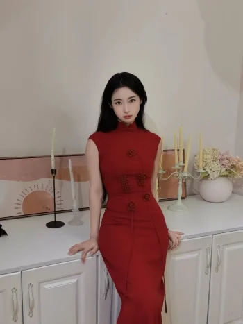 Women's Modified Chinese Red Qipao Dress - Woman in red qipao dress sitting on a white cabinet with candle decor, sleeveless form-fitting chinese dress qipao with floral appliques