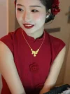 Women's Modified Chinese Red Qipao Dress - Close-up of red qipao dress with 3D rose appliques on the chest, bride wearing chinese dress qipao with gold necklace, bridal makeup scene