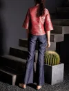 Back view of the women's modern Chinese red jacquard satin cheongsam top, showing the intricate pattern on the back and three-quarter sleeves; styled with flared jeans for a contemporary look