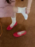 Red suede Mary Jane qipao shoes with white lace knit socks on feet, shown on a warm brown carpet for a cozy, vintage-inspired everyday style