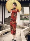 Woman in red floral vintage silk qipao dress holding a traditional yellow oil-paper umbrella, posing in a Chinese garden setting to highlight the retro charm of the cheongsam.