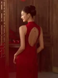 A close-up back view of a bride wearing a Red Wedding Backless Cheongsam Dress, highlighting the stunning open-back design with a delicate dangling gold chain. This Chinese Style Red Wedding Backless Cheongsam Dress combines traditional cheongsam tailoring with a bold, modern bridal aesthetic.