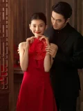 A romantic wedding portrait of a bride and groom, where the bride wears a vibrant red cheongsam wedding dress and holds a traditional double happiness paper cut. This Chinese style red wedding cheongsam blends cultural heritage with modern bridal charm.