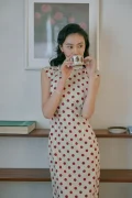 Close-up portrait of a woman sipping tea in a retro cotton qipao dress, highlighting the soft, breathable fabric and timeless cheongsam design.
