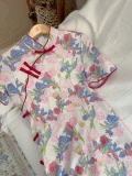 Retro plus size floral short sleeve cheongsam dress hanging on a wooden hanger, showing the full vibrant iris and rose print and classic red frog buttons of this plus size cheongsam dress.