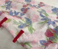 Close-up detail shot of a retro plus size floral short sleeve cheongsam dress, showing the vibrant iris and rose print fabric and traditional red frog buttons on this plus size cheongsam dress.