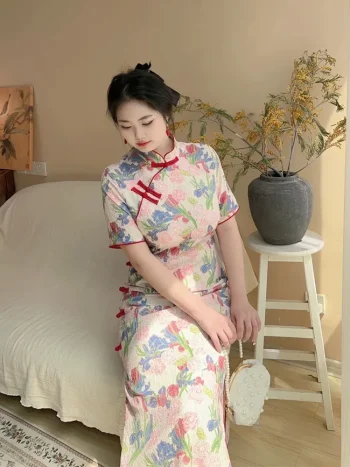 Plus size model wearing a retro floral short sleeve cheongsam dress, posing seated in a warm home setting with a pearl clutch, showcasing the elegant fit and vibrant print of this classic cheongsam.