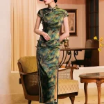 Full-body shot of a woman in a shanghai style retro qipao dress, mulberry silk cheongsam with leaf print and high slit, paired with a black wide-brim hat and heels in a vintage-style interior.